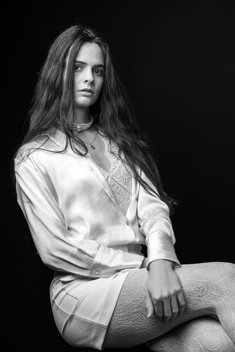 Stylish black and white portrait capturing a poised woman in elegant attire.